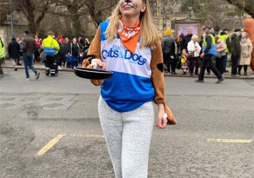 Katy in a dog outfit flipping a pancake for a Pancake Race