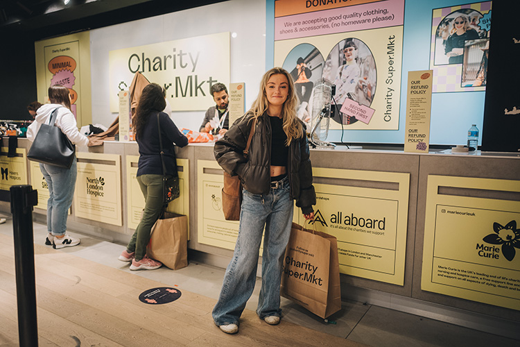 Young woman at the till with shopping bag at Charity Super Mkt