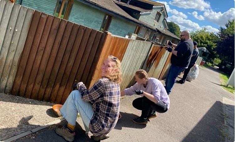 volunteer painting a fence on site