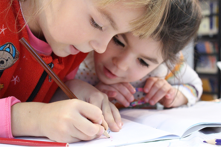 Two girls drawing or writing in collaboration